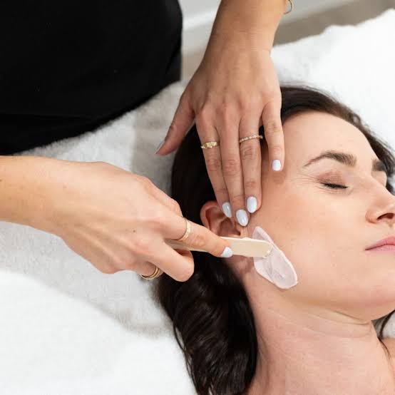 Esthetician waxing the sideburn and cheek area during side of face waxing