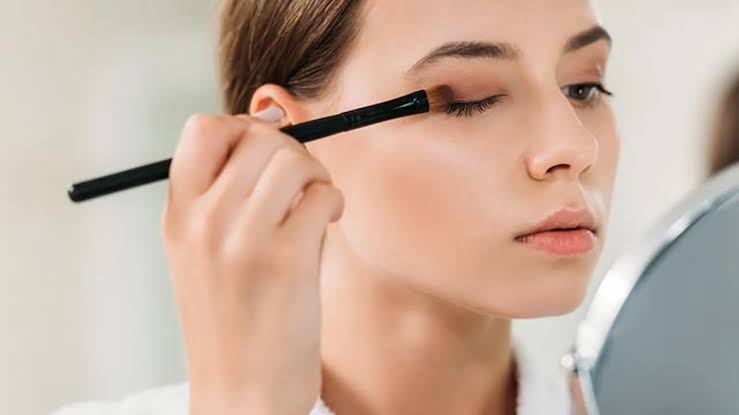 Woman applying makeup smoothly after side of face waxing