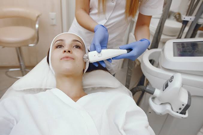 Esthetician preparing a client's skin during a side of face waxing treatment